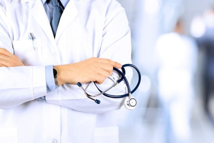 Portrait an unknown male doctor holding a stethoscope behind workers' compensation